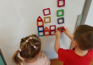 dzieci układają kompazycje z klocków magnetycznych na tablicy